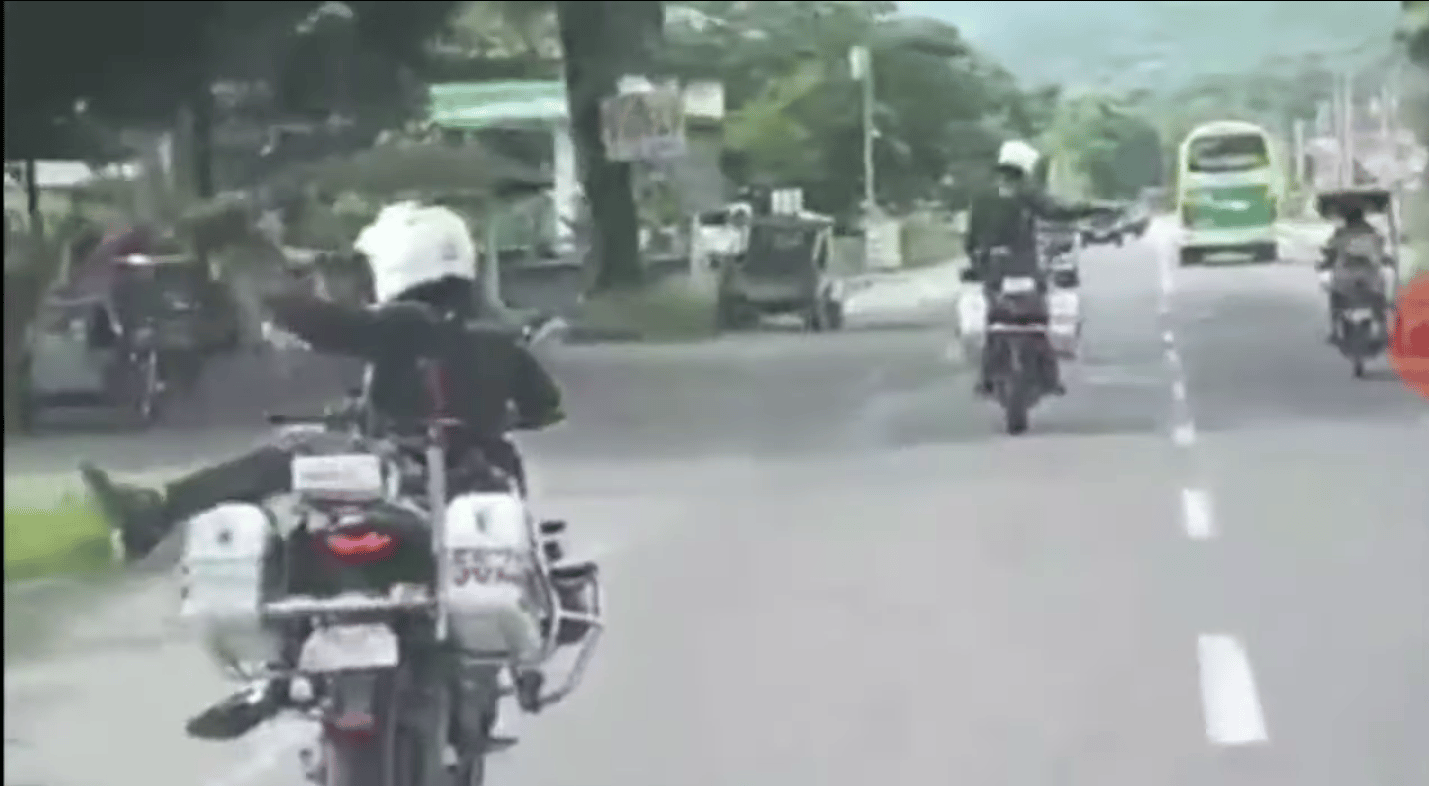 Screengrab from a phone cam video showing two police officers in uniform driving dangerously